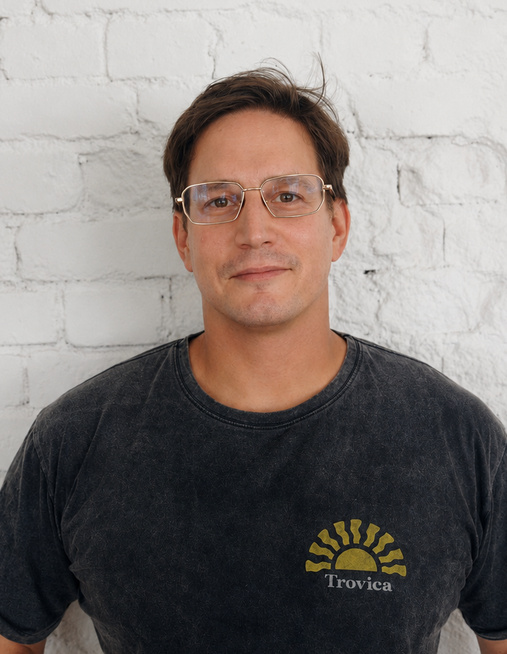 Robert Jakobson, digital product designer, standing against a white brick wall